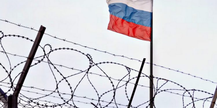 Колючий дріт та прапор РФ.