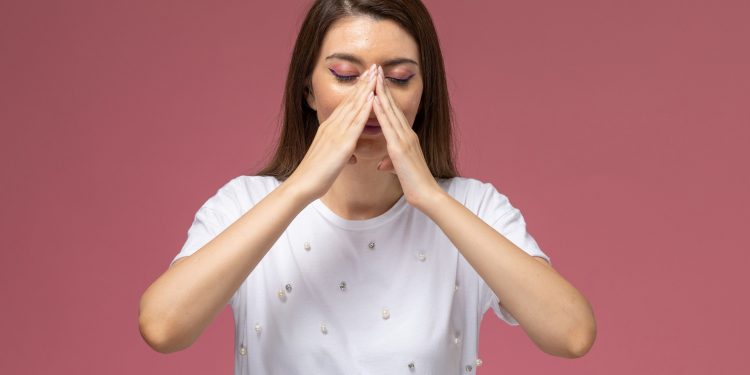 Жінка тримається за ніс.